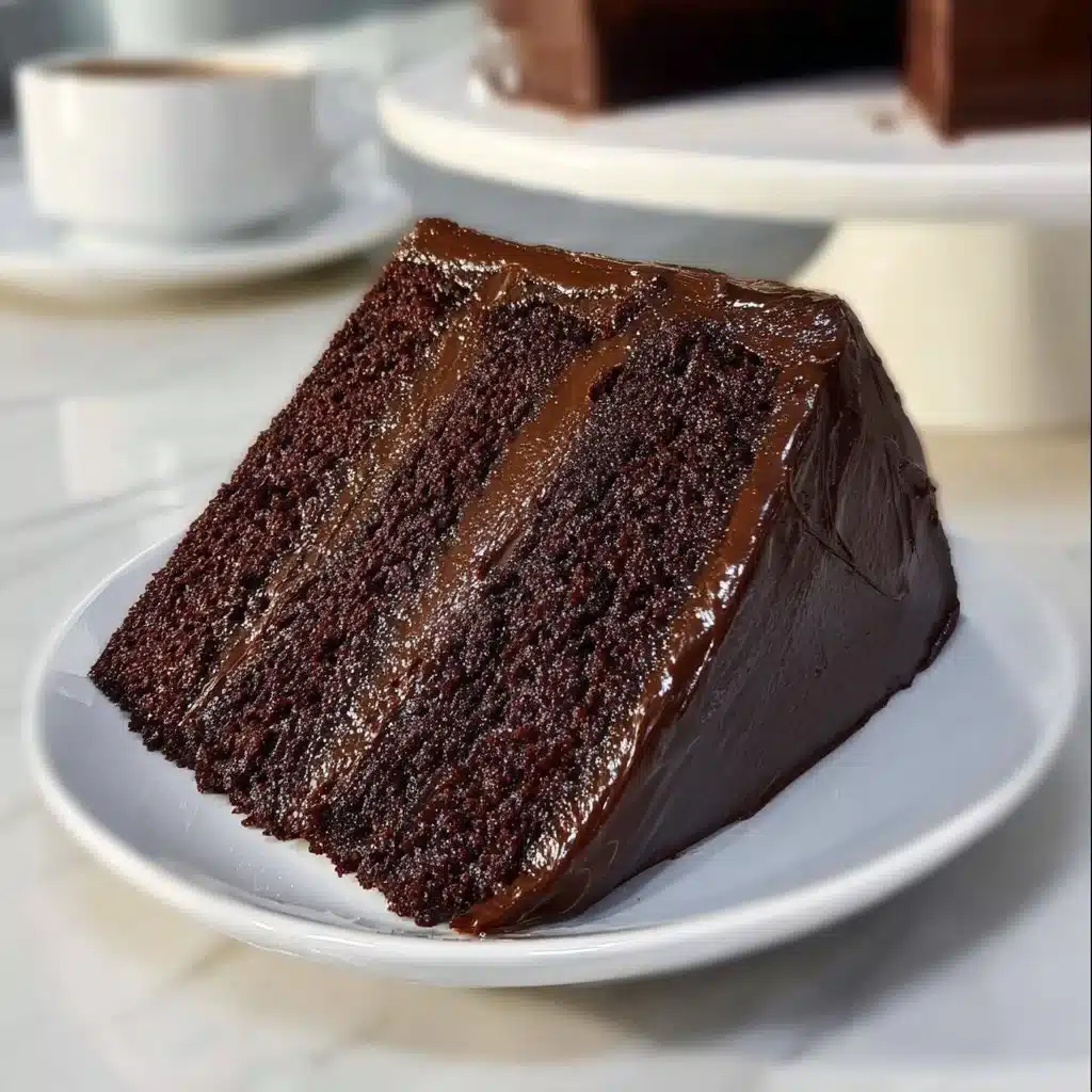 Indulge in Bliss with This Chocolate Fudge Cake Recipe 3 Deliciously rich Chocolate Fudge Cake served on a plate with decorative chocolate shavings